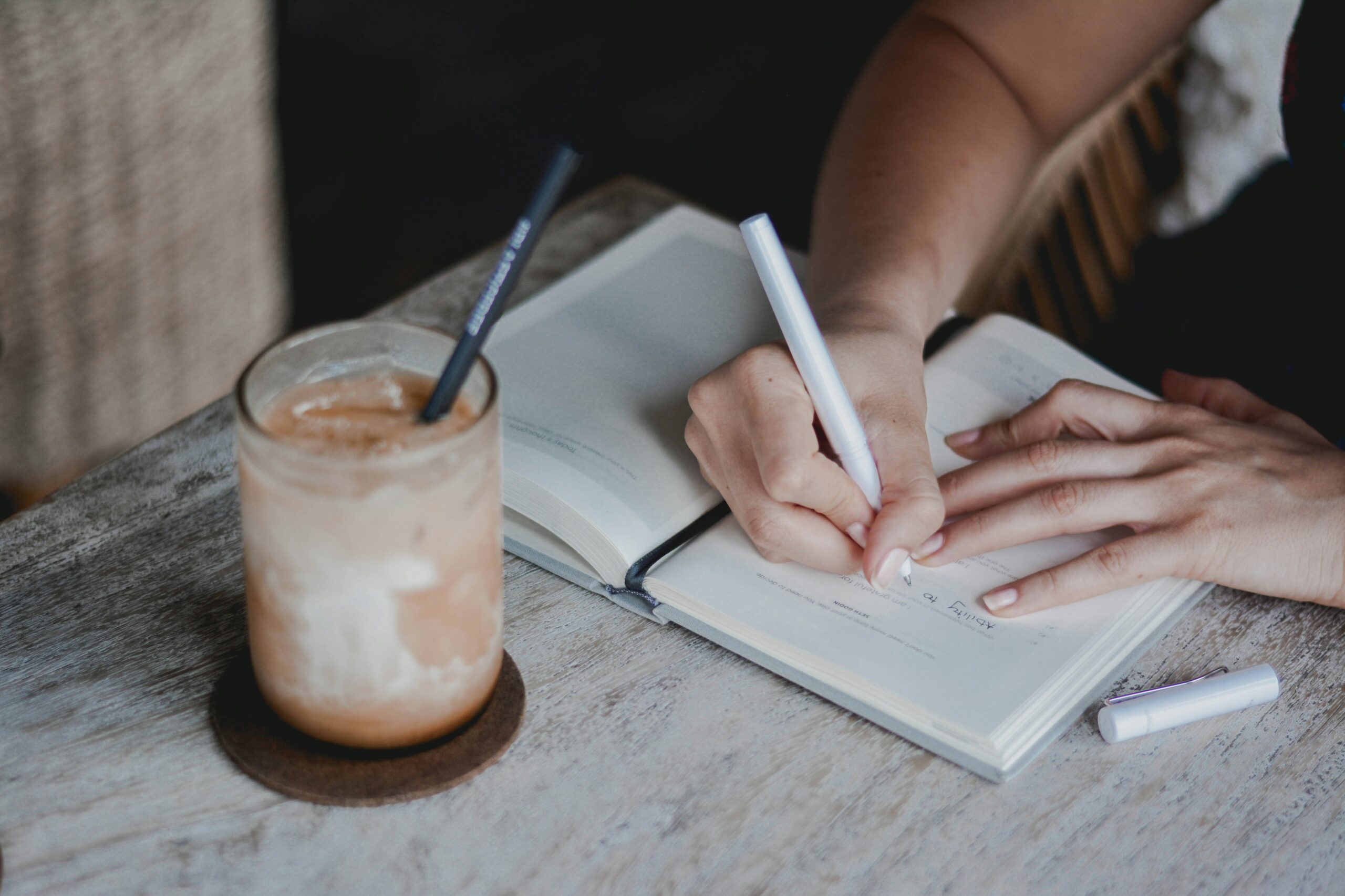 person in white knit sweater writing on white paper